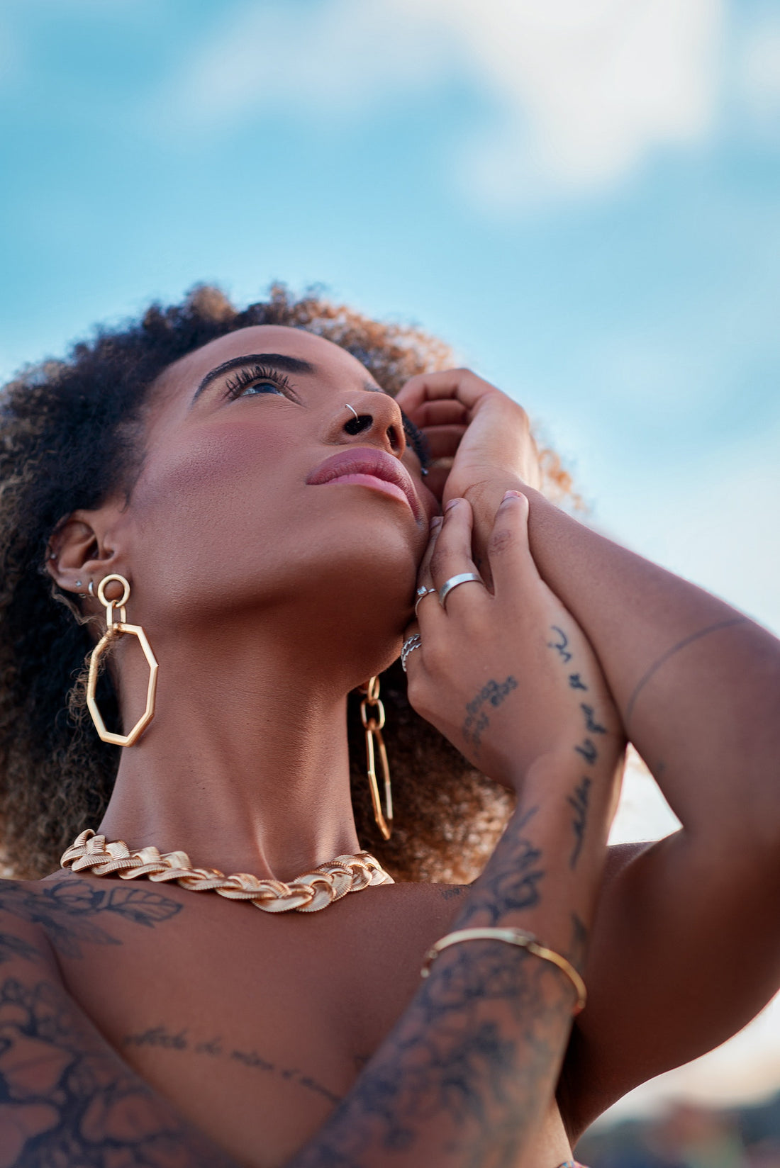 black woman wearing lots of jewelry on a sunny day and looking thoughtfully into the eye